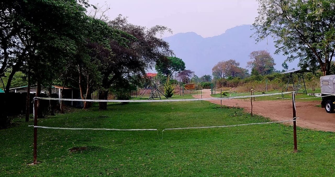 Open lawn and volleyball net with Nilgiri hills in the background
